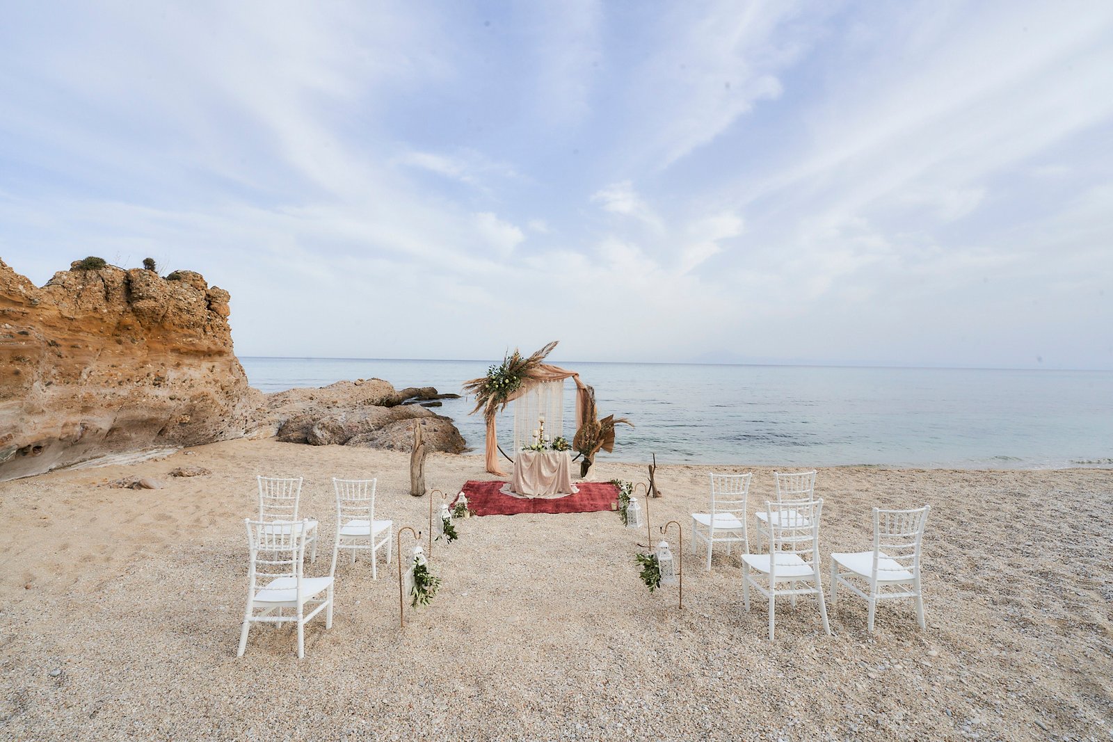 Elegant beach wedding setup on Thassos with white chairs and floral arch for a seaside ceremony