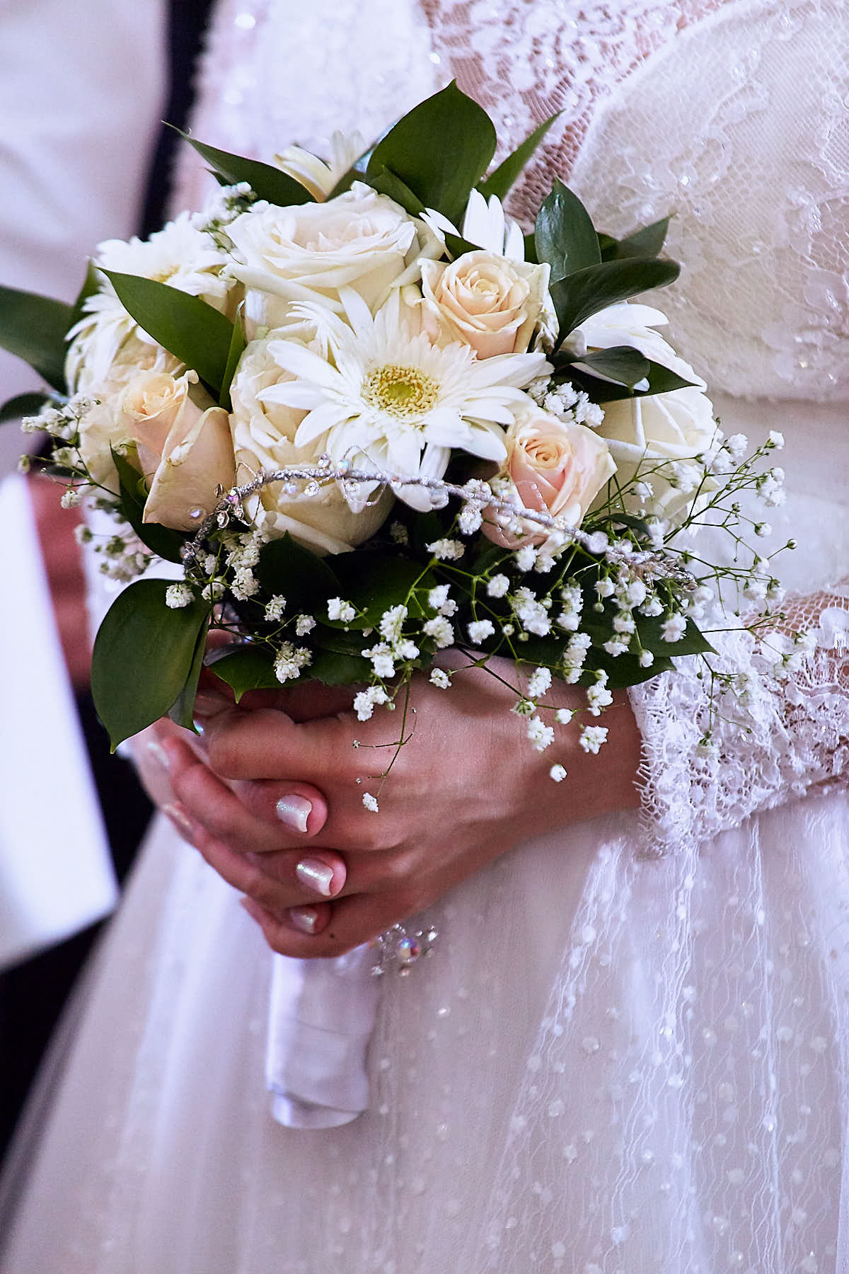 Detail of the bride's hands holding the white bouquet
