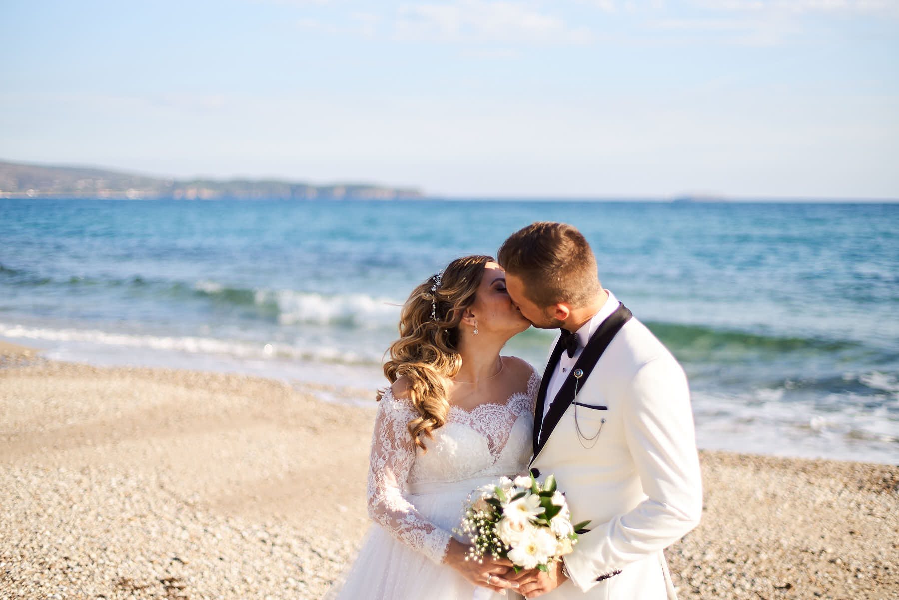 Bride kissing her groom by the sea