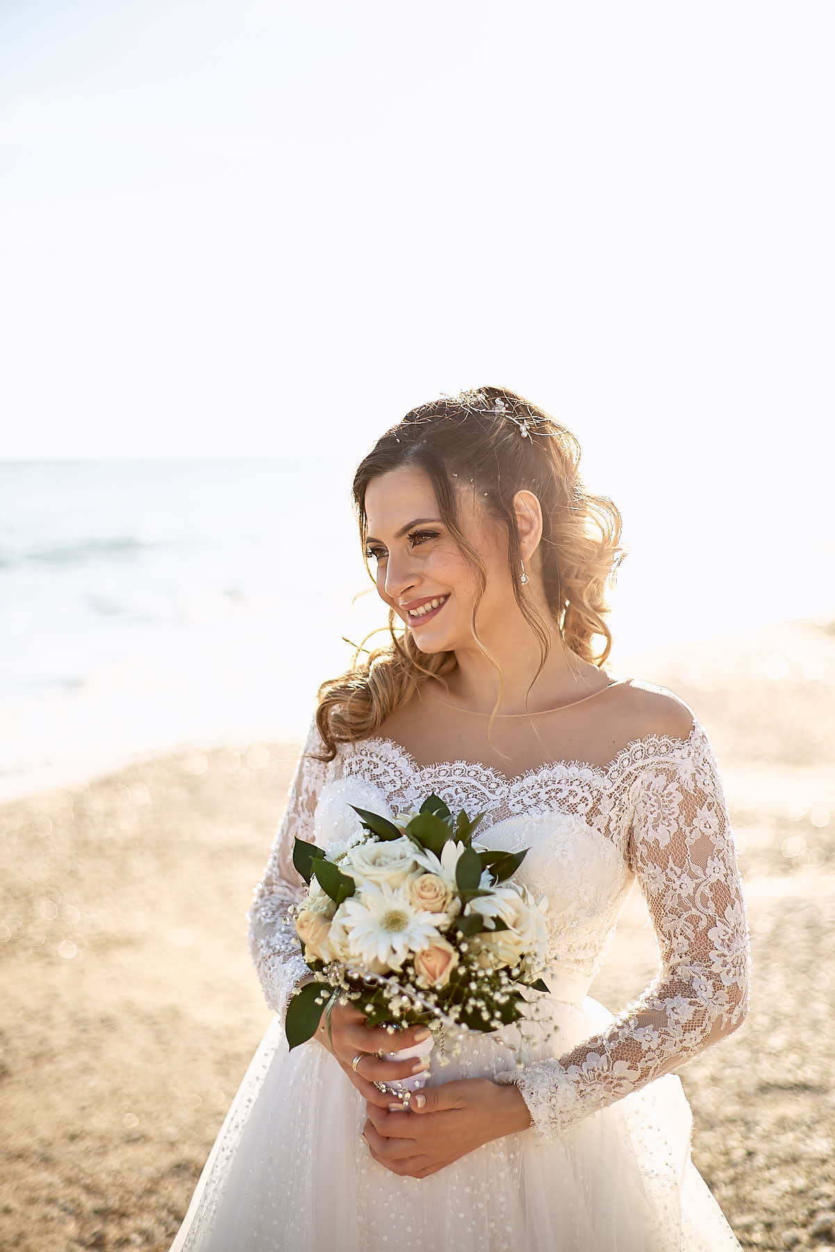 Bride holding flowers, smiling, sunset shining behind her bright