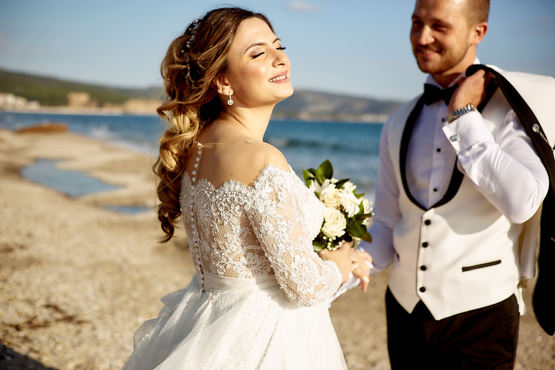 Bride smiling while sunbathing, groom smiling looking at her wife