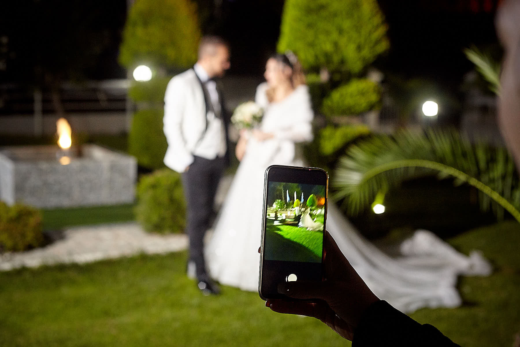 groom and bride at the background, smart phone screen capturing this moment