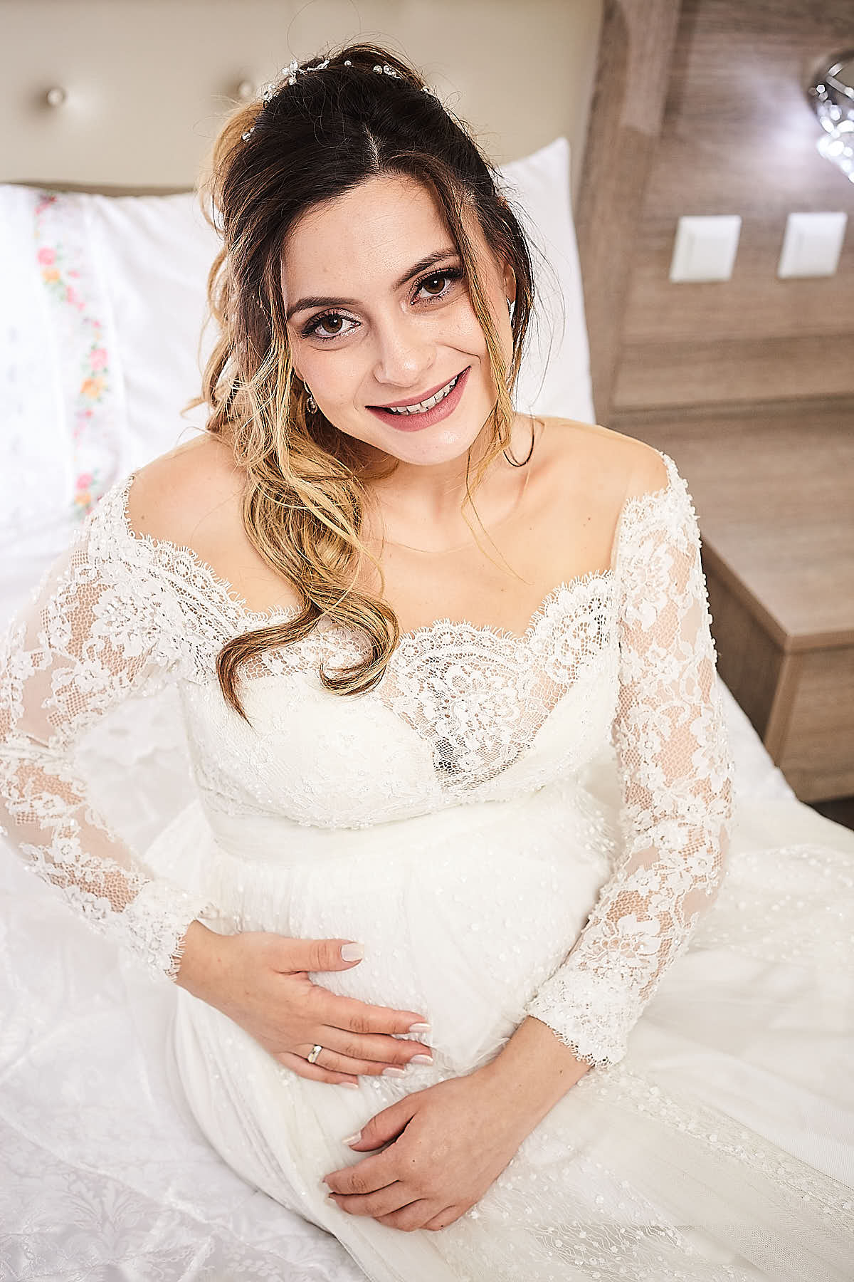 Pregnant bride touching her belly and smiling