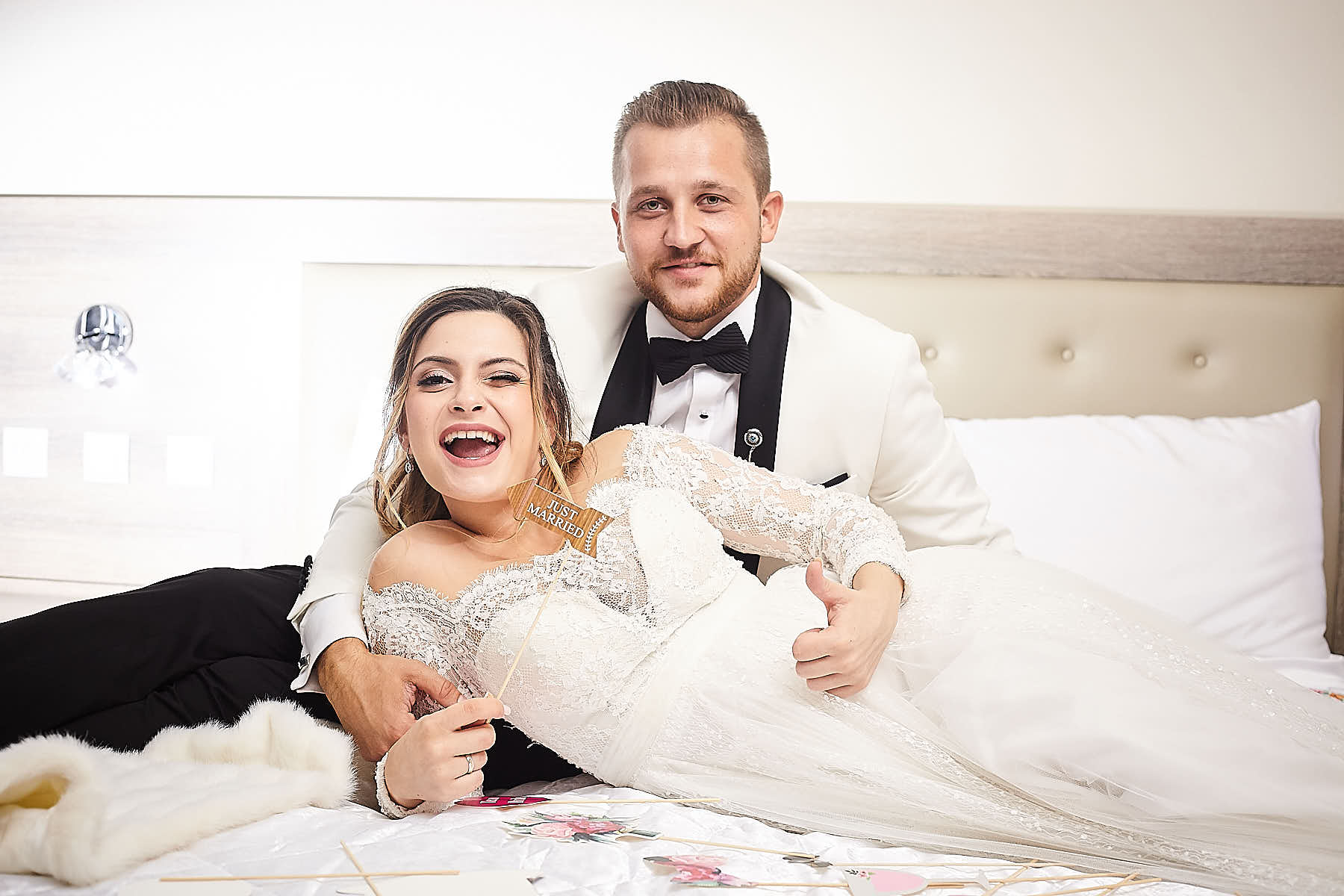 couple relaxing, bride holding a "Just Married" sign and giving a thumbs up and groom smiling at the camera