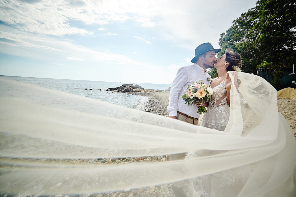 Groom and bride kissing at the beach