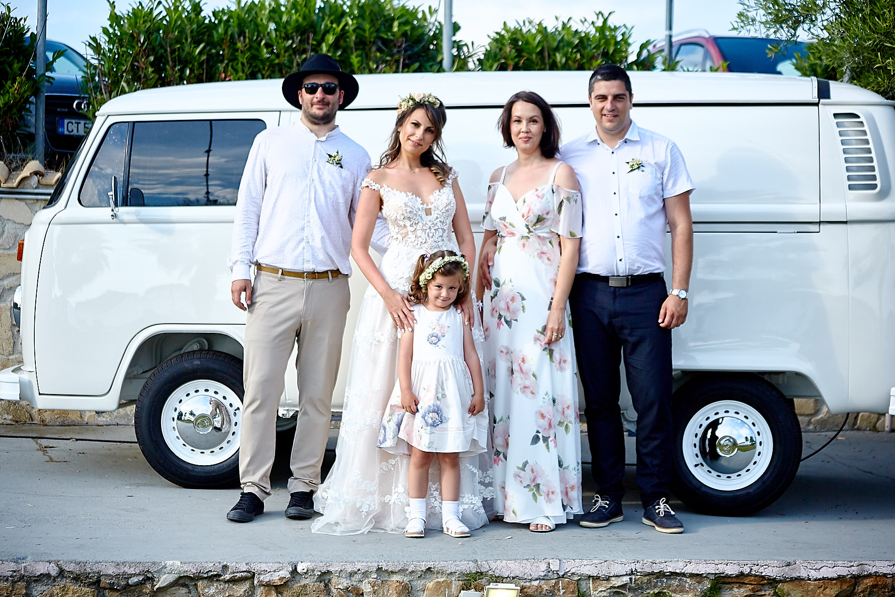 Newlyweds with their family in front of a boho style van at Aelia Bar Restaurant for their beach wedding in Halkidiki