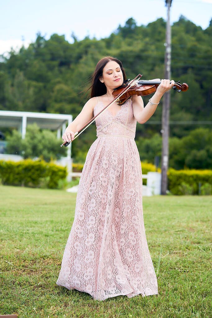 Violin performance at modern seaside proposal setup
