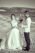 black and white, groom and bride at the beach, beach is with pebbles, there are few waves and mountains are in the background