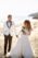 Groom looking at bride, bride holding bouquet at the beach