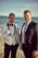 Groom with his jacket on his shoulder with a relative besides him, sea and sky on the background