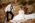 groom looking at his bride while holding bouquet, bride sitting on the ground and looking at the bouquet