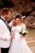 groom carresing bride's hair, bride holding bouquet at the beach